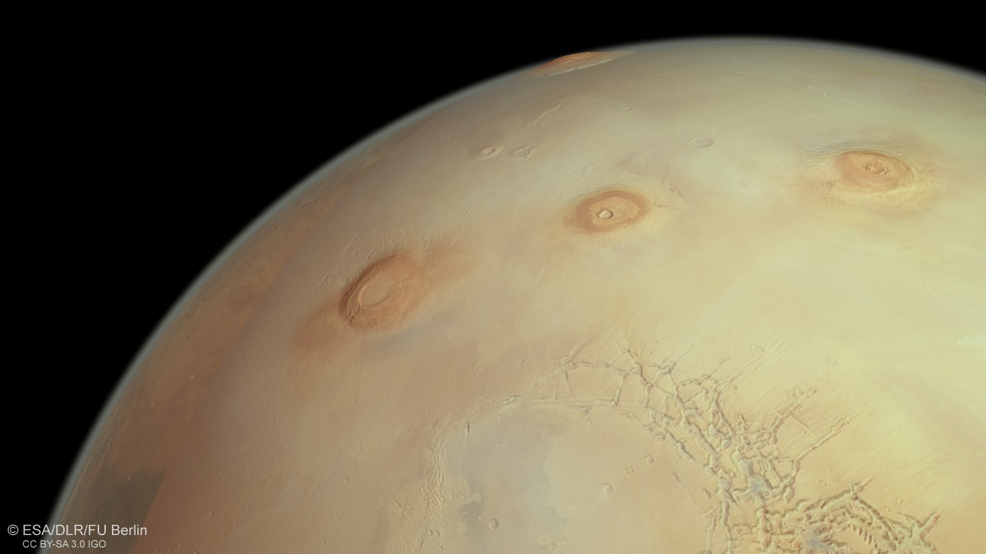 Wie gigantische Insektenstiche präsentieren sich die drei großen Tharsis-Vulkane Arsia Mons, Pavonis Mons und Ascraeus Mons sowie der höchste Vulkan im Sonnensystem, Olympus Mons, am Horizont auf der Tharsis-Aufwölbung am Marsäquator.