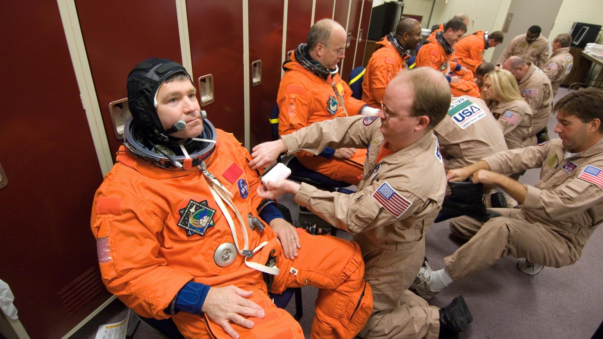 Die Techniker der United Space Alliance (USA) helfen der Crew in die Trainingsanzüge
