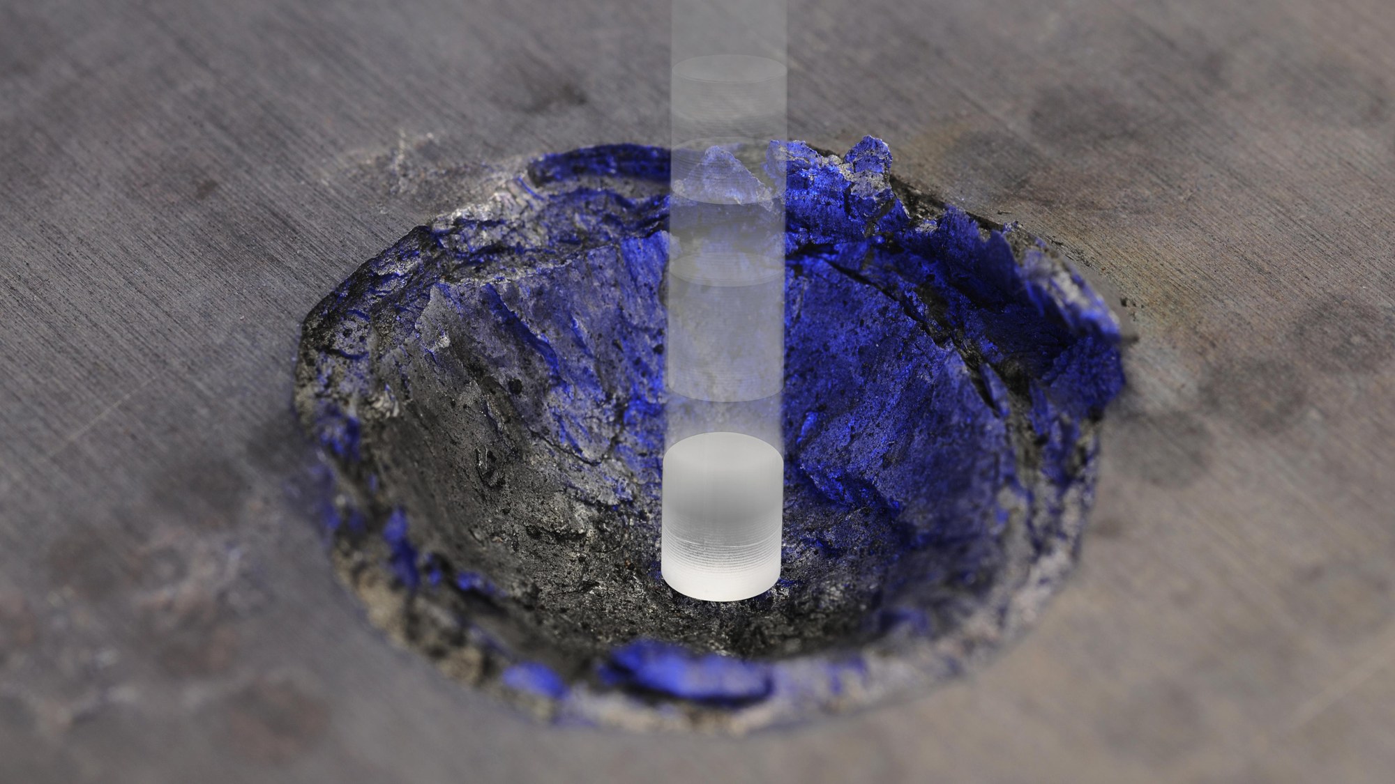 Ein Laborversuch zeigt den Einschlagkrater in einem Aluminiumblock nach einem Beschuss mit einem Kunststoffteil bei über sechs Kilometern pro Sekunde.