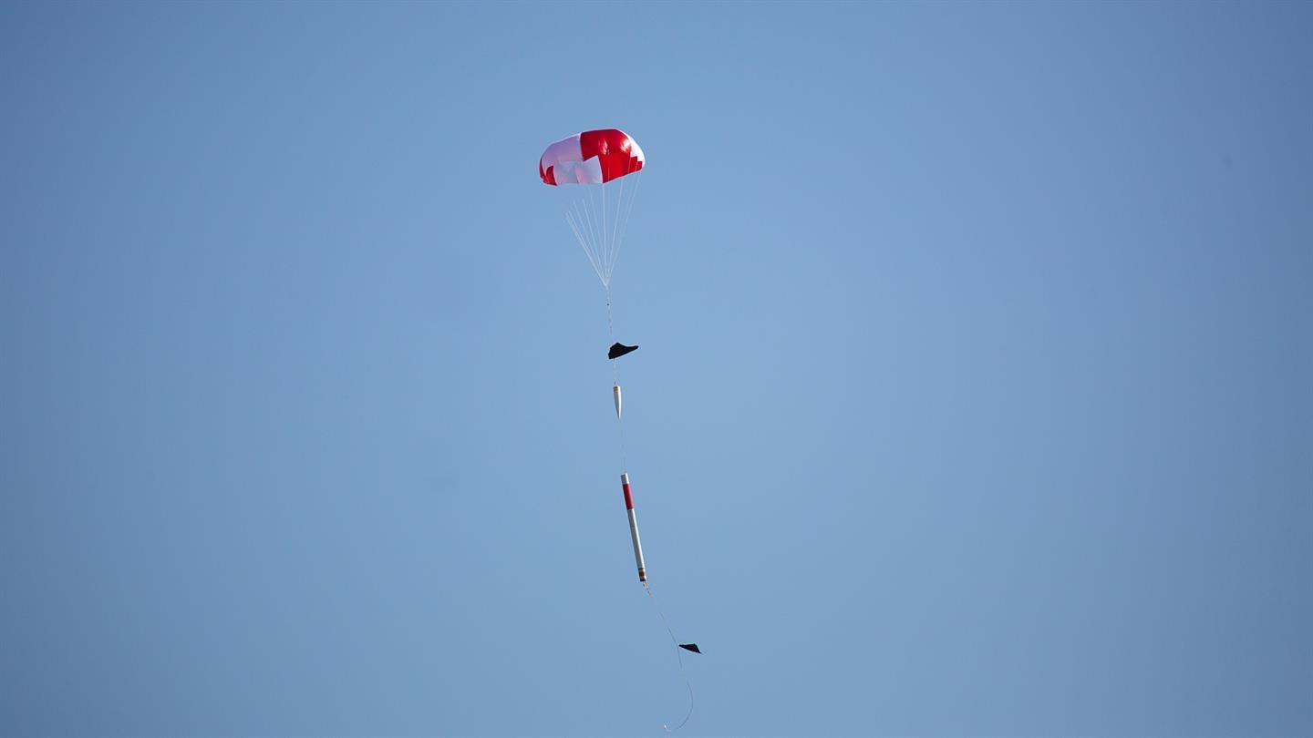 Eine Rakete kommt nach ihrem Flug am Fallschirm zur Erde zurück.