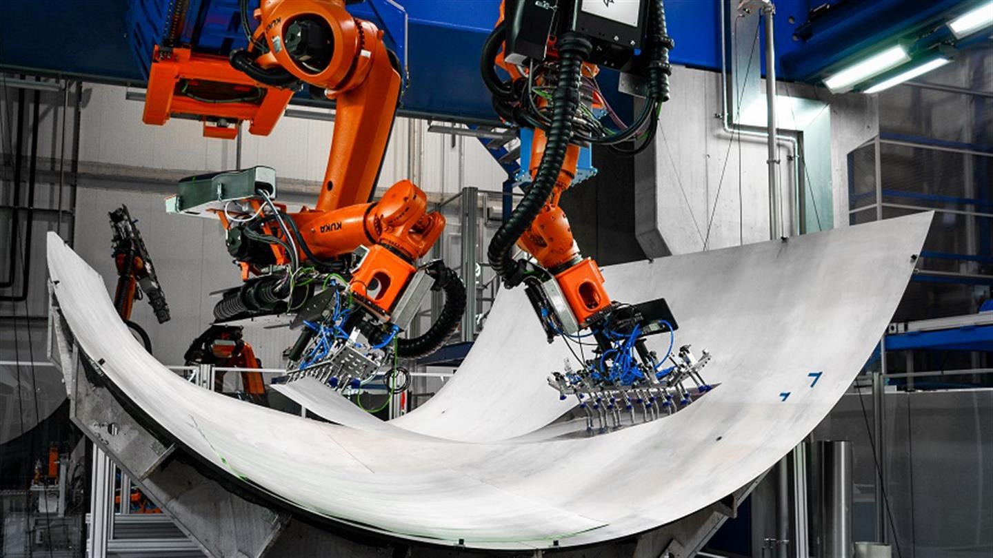 Zwei Roboter legen kooperierend das Aluminium eines Demonstrators in der Multifunktionszelle ab.