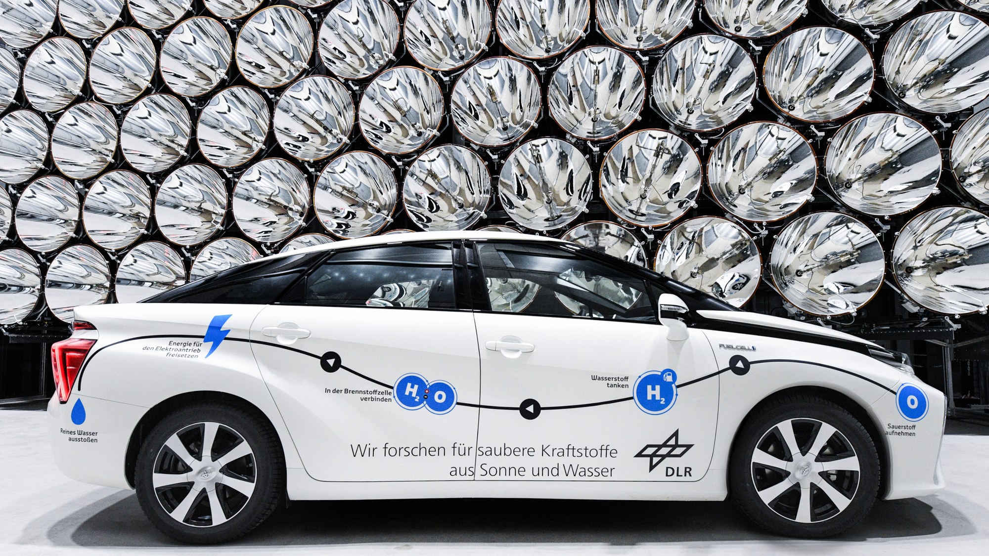 A hydrogen-powered fuel cell vehicle stands in front of the Synlight's high-performance radiators.