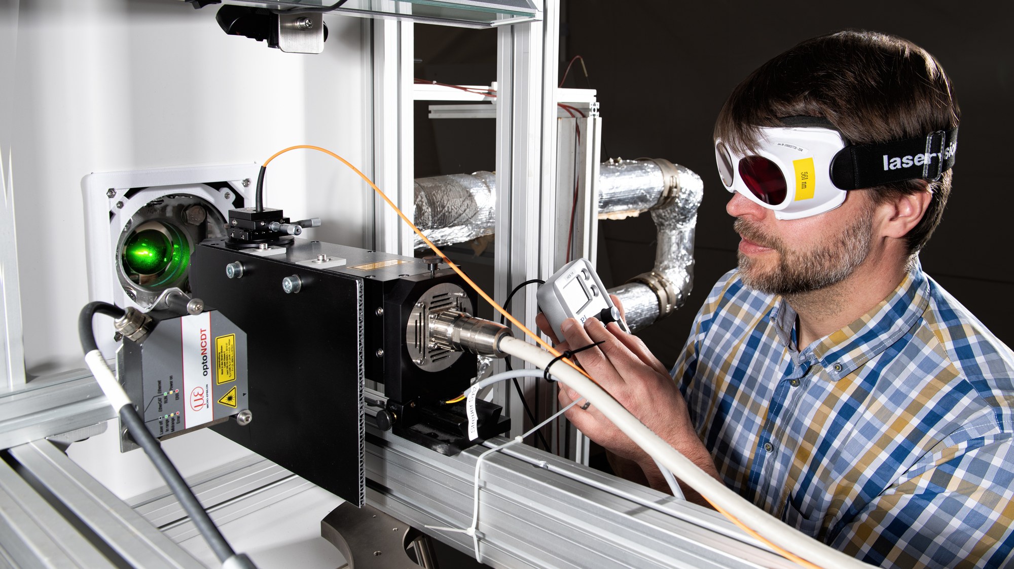 A scientist wearing safety goggles works on an experimental setup for Laser Doppler Velocimetry (LDV).
