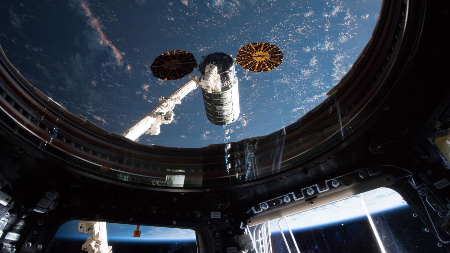 The multi-functional robot arm Canadarm2 reaches for the Cygnus transporter of the OA-9 mission.