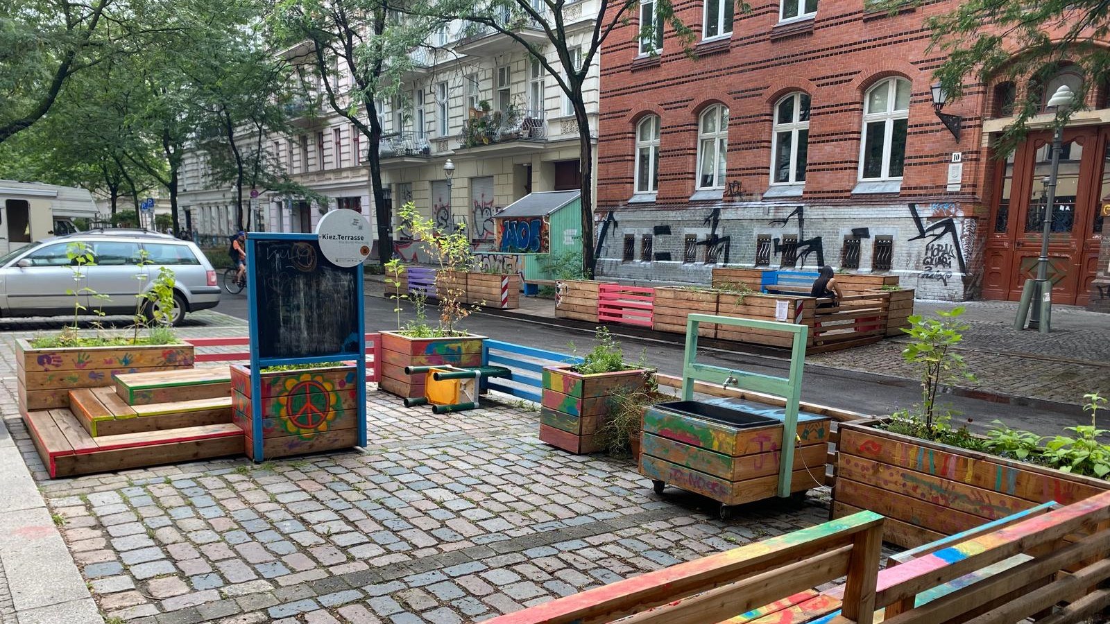 A view of Böckhstraße. Some of the parking bays have been converted into neighborhood terraces. The wooden structures contain planted tubs that further green the street.