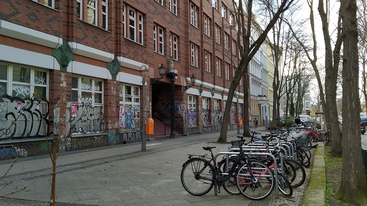 The school is seen from the outside. Several bicycles are parked there.