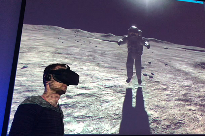 Tobias Bohnhardt führt das Publikum durchs Weltall. Hier ist er mithilfe einer VR-Brille zusammen mit Neil Armstrong auf dem Mond. Bild: DLR