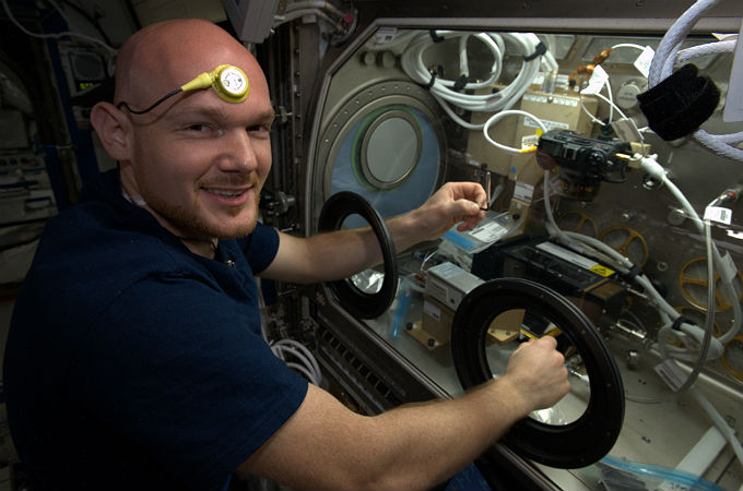 Alex mit einem Temperatur-Sensor. Gleichzeitig ist er an der Handschuhbox mit einem Experiment zur Verbrennungsforschung beteiligt. Bild: NASA, ESA