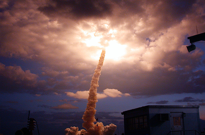 Eine Raumfähre durchstößt auf dem Weg ins All die Wolkendecke. 
Bild: NASA