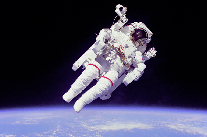 Bruce McCandless beim ersten Spacewalk ohne Leine. Man erkennt den großen „Rucksack“, die Steuereinheit mit Düsen, mit der er um die Raumfähre herumfliegen und auch wieder sicher in die Schleuse zurückkehren konnte. 
Bild: NASA