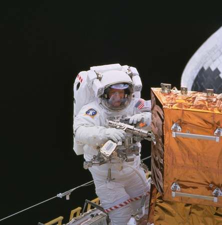 Claude Nicollier aus der Schweiz. Im Auftrag der Europäischen Weltraum-Organisation ESA repariert er das Weltraum-Teleskop Hubble. Dieser Satellit wurde zuvor mit einem Roboter-Arm eingefangen und in die Ladebucht der Raumfähre gehoben.
Bild: NASA, ESA